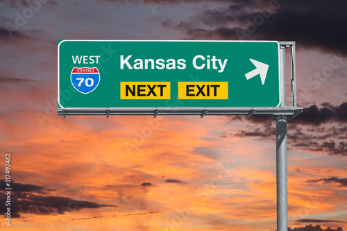 Kansas City Missouri route 70 freeway next exit sign with sunset sky.