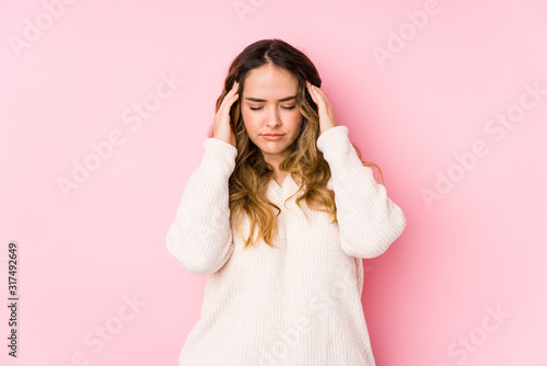 Young curvy woman posing in a pink background isolated touching temples and having headache.