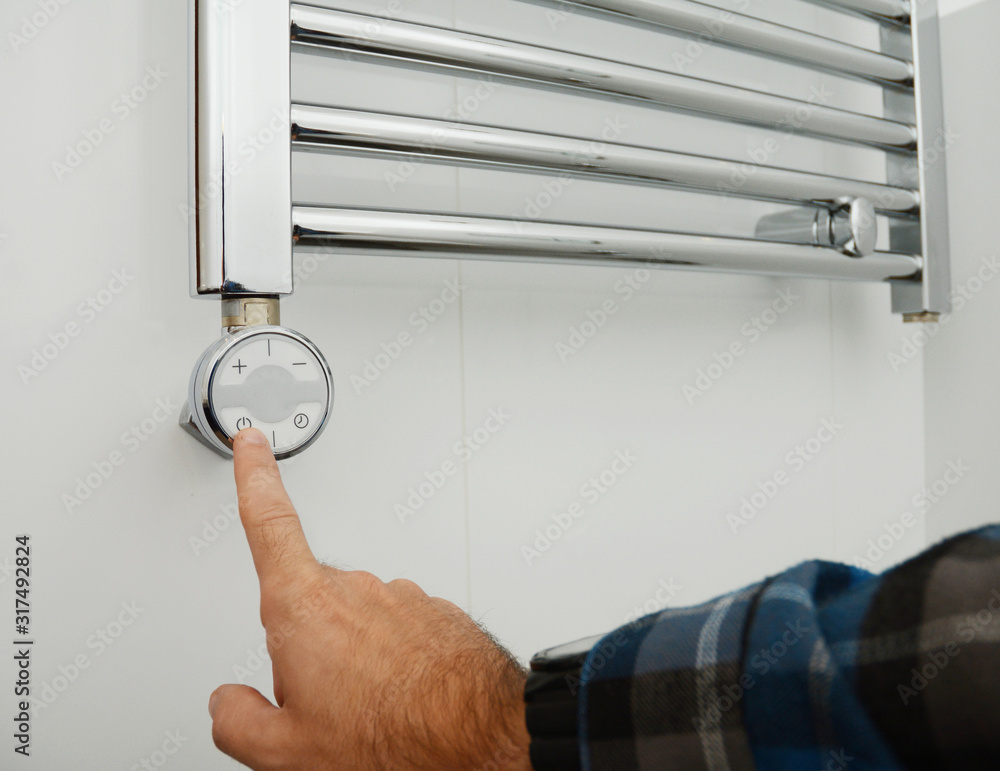 Man switch on electric towel rail radiator. Towel Radiator Heating ...