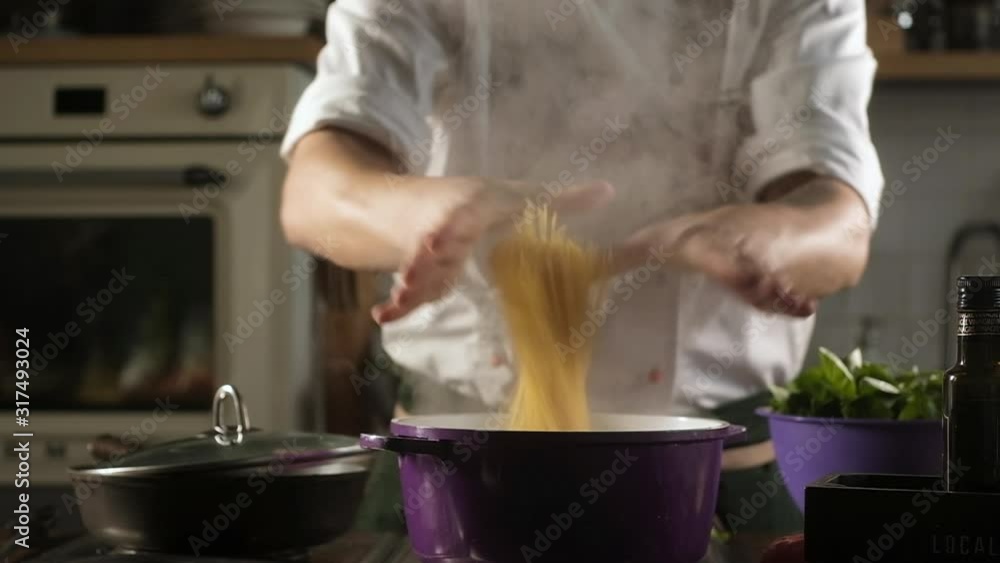 cook throws spaghetti into pot of boiling water. Preparation of ingredients by male chef to prepare noodles for pasta. Cooking in restaurant kitchen. Modern cooking. Food ingredients for gourmets cook throws spaghetti into pot of boiling water. Preparation of ingredients by male chef to prepare noodles for pasta. Cooking in restaurant kitchen. Modern cooking. Food ingredients for gourmets