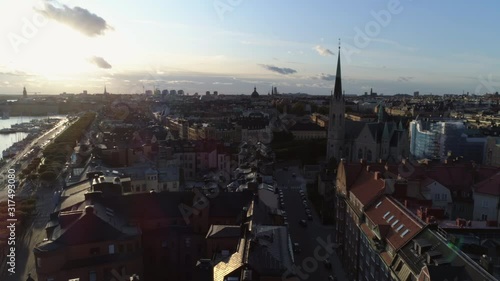 Drone shot flying over rooftops of Stockholm. Aerial view of Östermalm district at sunset. Oscar's Church (Oscarskyrkan), apartment buildings and street. Capital city of Sweden, cityscape skyline photo