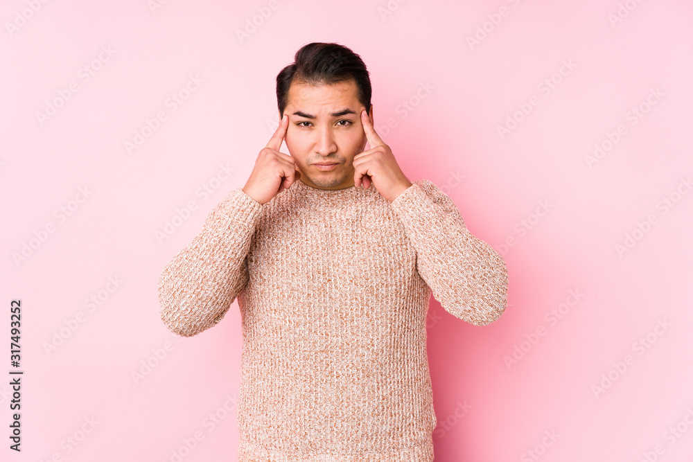 Young curvy man posing in a pink background isolated focused on a task, keeping forefingers pointing head. Young curvy man posing in a pink background isolated focused on a task, keeping forefingers pointing head.