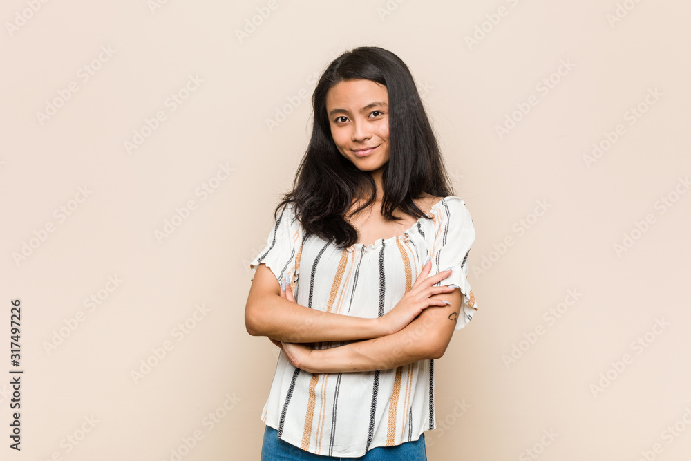 Young cute chinese teenager Young blonde woman wearing a coat against a pink background who feels confident, crossing arms with determination. Young cute chinese teenager Young blonde woman wearing a coat against a pink background who feels confident, crossing arms with determination.