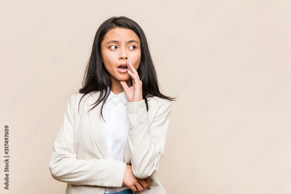 Young business chinese woman is saying a secret hot braking news and looking aside Young business chinese woman is saying a secret hot braking news and looking aside