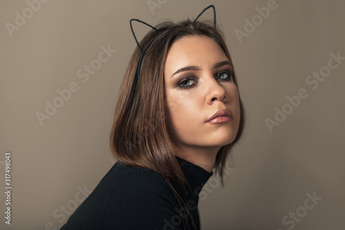 Canvas-taulu Teen girl with cat ears headband and perfect makeup on brown background