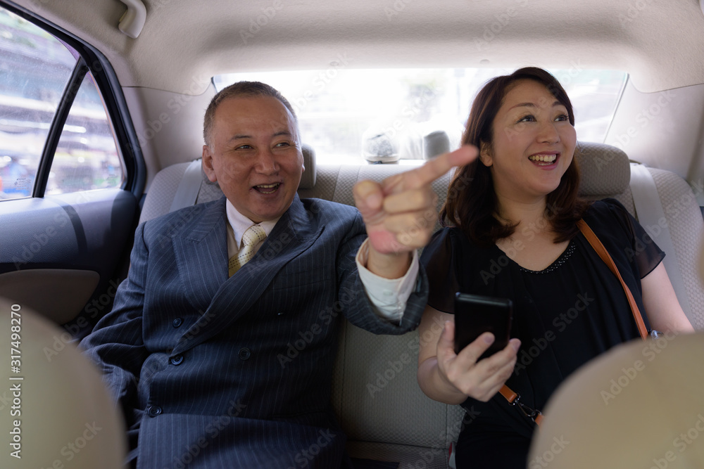 Mature Asian businessman and mature Asian woman riding car together Mature Asian businessman and mature Asian woman riding car together