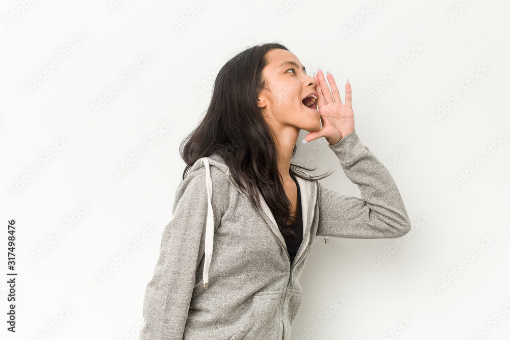 Young fitness chinese woman shouting and holding palm near opened mouth. Young fitness chinese woman shouting and holding palm near opened mouth.