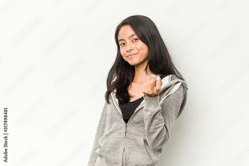 Young fitness chinese woman pointing with finger at you as if inviting come closer. Young fitness chinese woman pointing with finger at you as if inviting come closer.