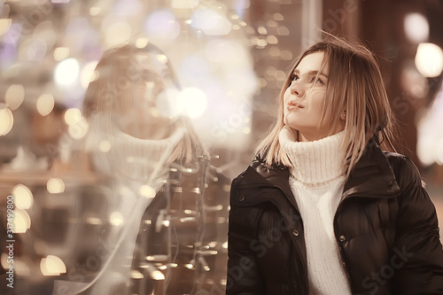 girl christmas lights evening decorated city, a young model on the background of urban decorations and garlands, night city lights