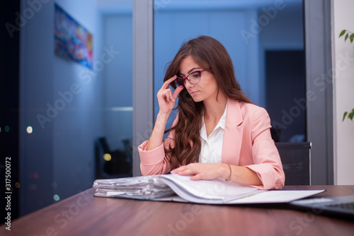 Young woman in the office holding her glasses