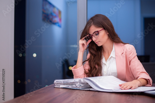 Young woman in the office holding her glasses