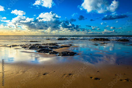 playa con olas nubes y cielo azul arena reflectante