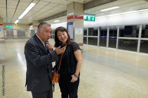 Mature Asian businessman and mature Asian woman at the subway station together © Ranta Images