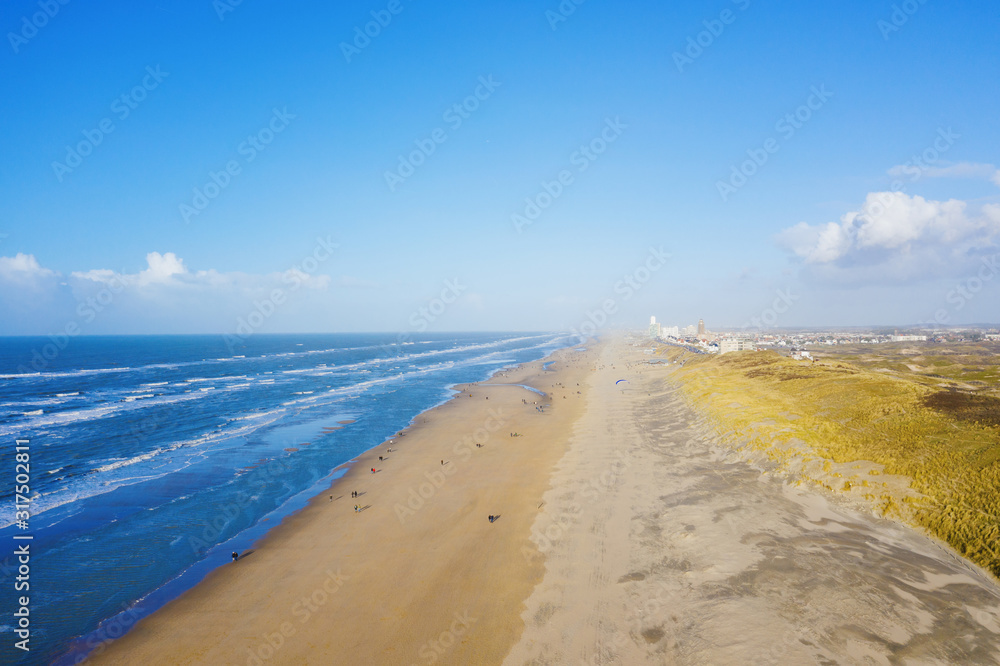 People walking on a north sea sandy beach near Zandvoort, Netherlands, aerial drone view