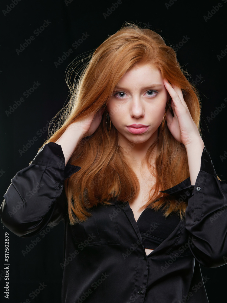Fototapeta premium young girl with long red hair on a black background