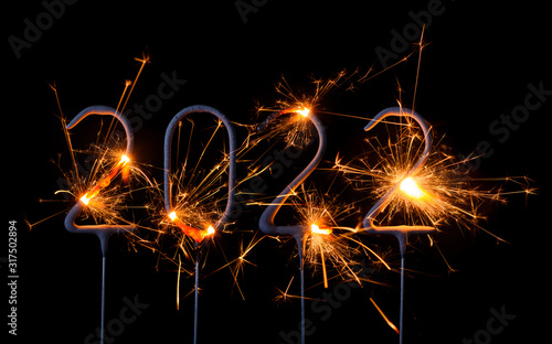 Happy New Year 2022. Digits of year 2022 made by burning sparklers isolated on black background.