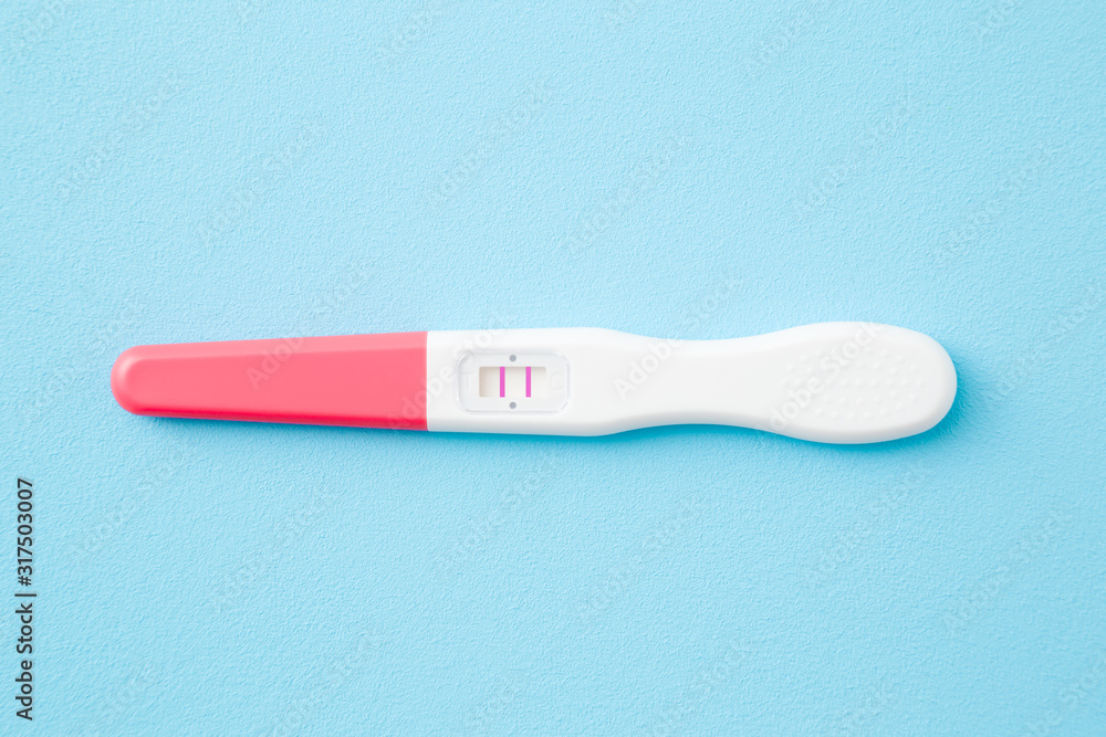 Pregnancy test with two stripes on light blue table background. Pastel color. Positive result. Closeup. Top down view. Pregnancy test with two stripes on light blue table background. Pastel color. Positive result. Closeup. Top down view.
