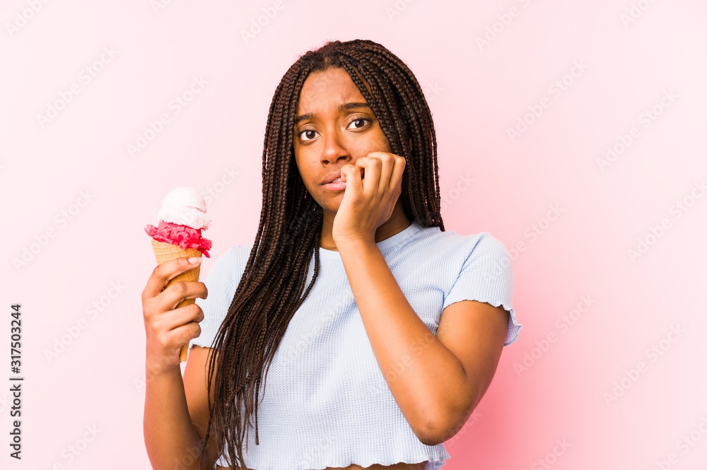 Young african american woman holding an ice cream isolated biting fingernails, nervous and very anxious.