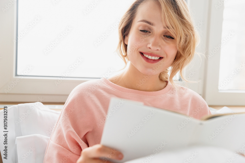 Woman indoors at home lies in bed reading book. Woman indoors at home lies in bed reading book.