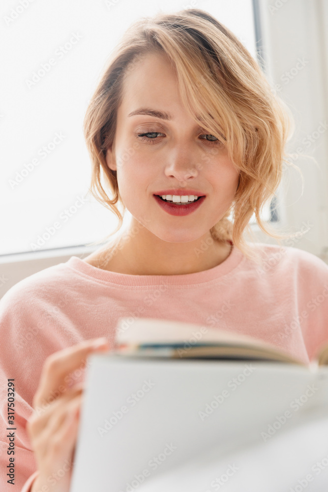 Woman indoors at home lies in bed reading book. Woman indoors at home lies in bed reading book.
