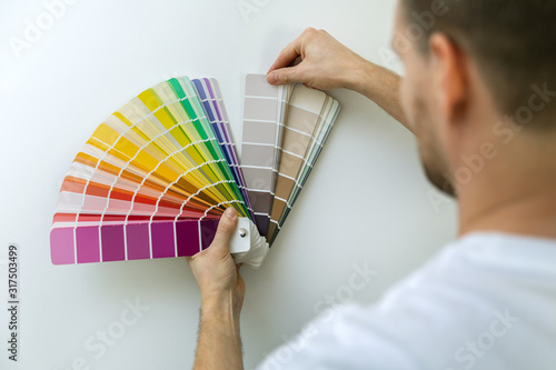 фотографія man selecting paint color from swatch for room wall