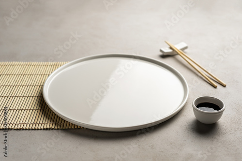 White empty plate for sushi or rolls for product placement, on a concrete background shot at forty-five degrees.