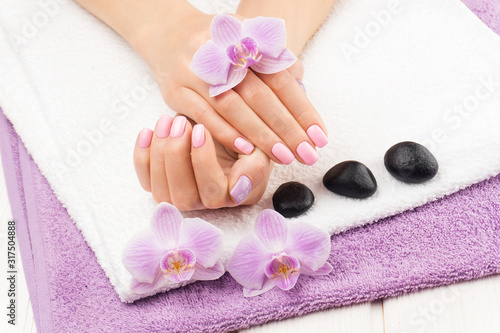 beautiful pink manicure with decor, orchid, towel on the white wooden table. spa
