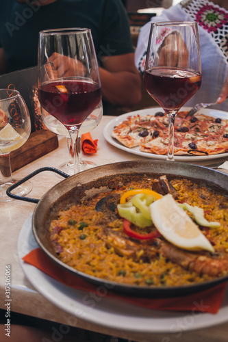 Typical spanish seafood paella in traditional pan. glasses with Spanish sangria in the background. dinner in a restaurant.