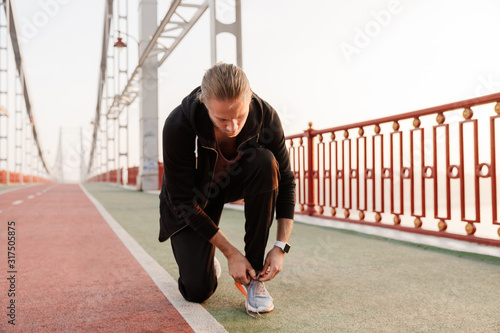 Attractive young fit sportsman working out on a bridge