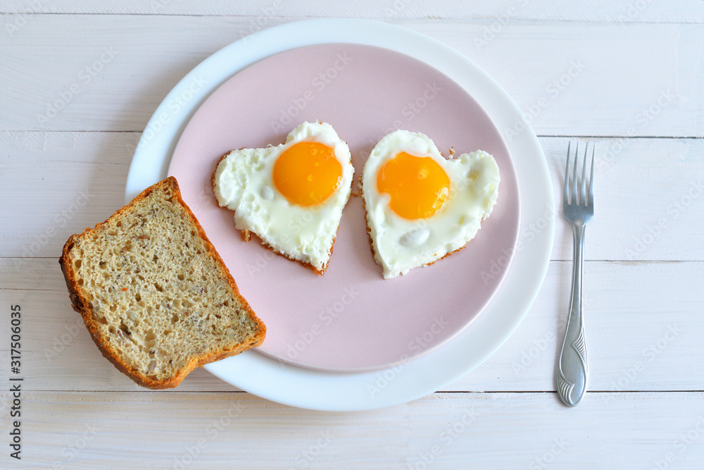 Two fried eggs on pink plate for healthy breakfast on wooden table. top view Two fried eggs on pink plate for healthy breakfast on wooden table. top view