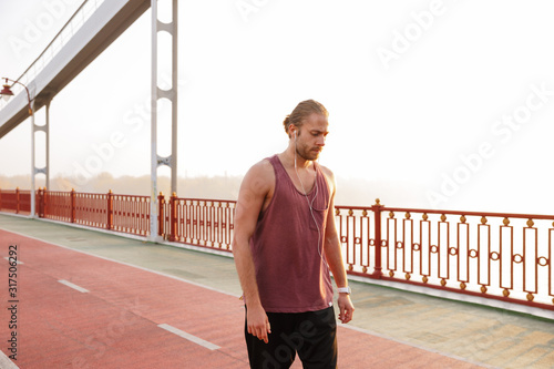 Attractive young fit sportsman working out on a bridge