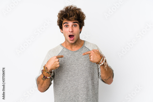 Young caucasian man against a white background isolated surprised pointing with finger, smiling broadly.
