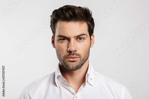 Image of young caucasian businessman posing and looking at camera