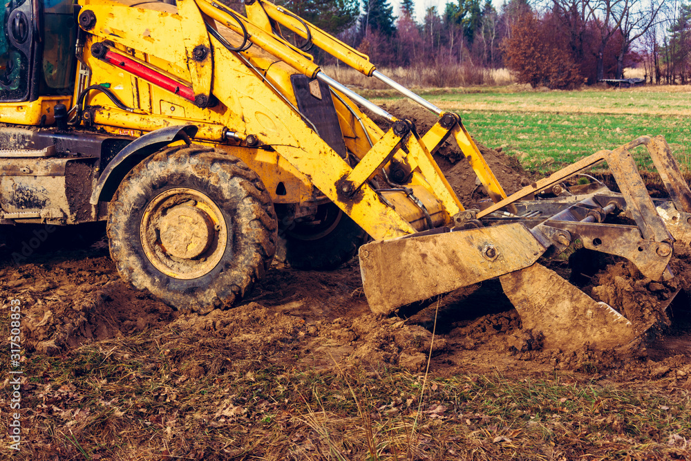 The excavator is digging the ground for the foundation and construction of a new road in the village. The excavator is digging the ground for the foundation and construction of a new road in the village.