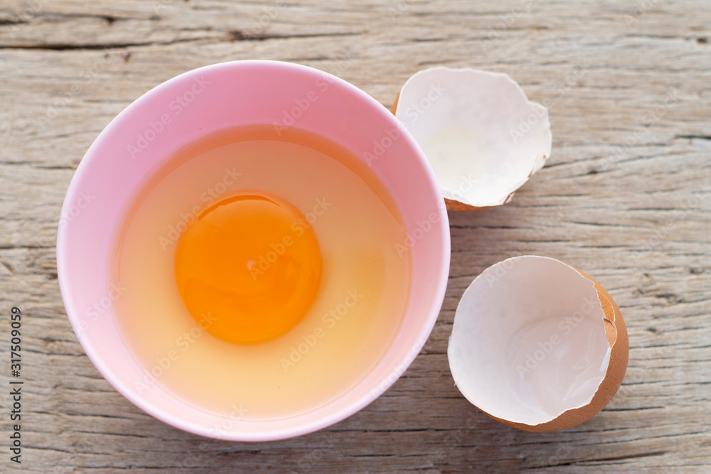 The brown chicken eggs in a pink bowl and a wooden table as a background. The brown chicken eggs in a pink bowl and a wooden table as a background.