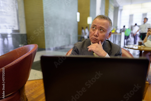 Mature Asian businessman relaxing inside the coffee shop