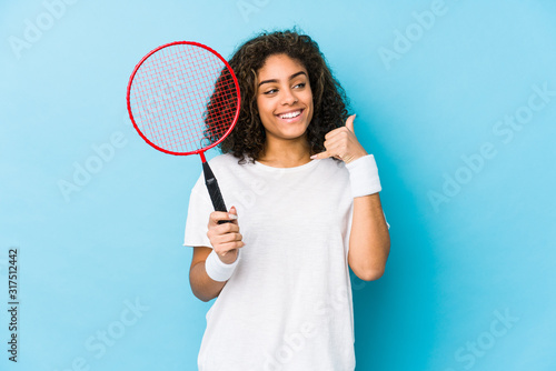 Young african american woman playing badminton showing a mobile phone call gesture with fingers. © Asier