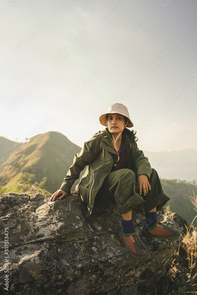 A female hiker sitting on the rock over the mountain