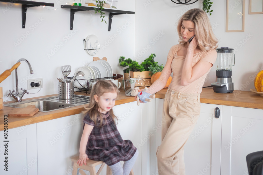 Young mother working from home on laptop with her toddler daughter. Home office, working mother concept Young mother working from home on laptop with her toddler daughter. Home office, working mother concept