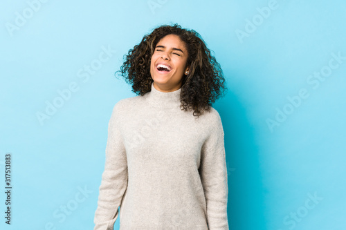 Young african american curly hair woman relaxed and happy laughing, neck stretched showing teeth.