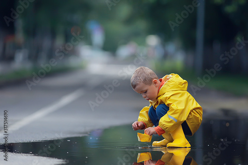 a boy plays boats in a puddle / childhood, walk, autumn game in the park, a child on a walk
