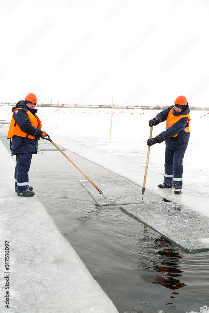 Workers rafting ice blocks along a channel cut out by a frozen lake Workers rafting ice blocks along a channel cut out by a frozen lake