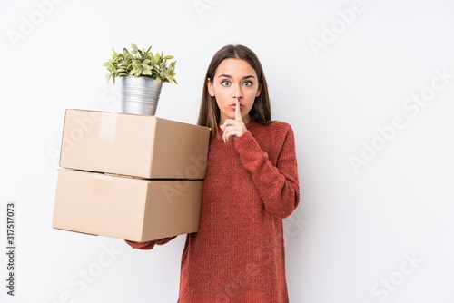 Young caucasic woman holding boxes isolated keeping a secret or asking for silence.