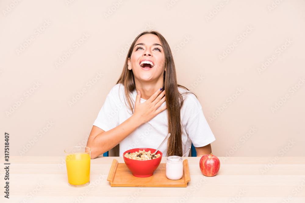 Young caucasian woman having a breakfast isolated laughs out loudly keeping hand on chest.