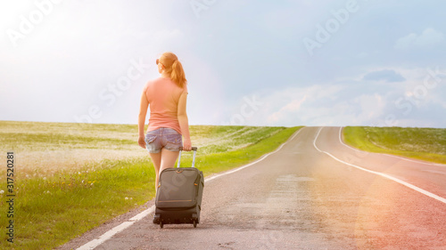 Photography Girl traveler goes with a suitcase on the road in the summer on a sunny day