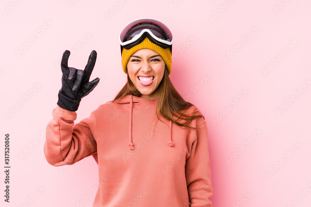 Young caucasian woman wearing a ski clothes isolated showing a horns gesture as a revolution concept.
