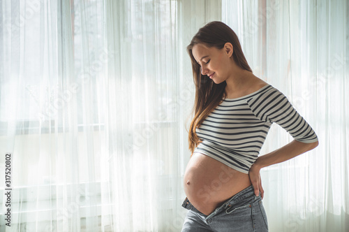Happy pregnant woman with big belly by the window. Concepts of pregnancy and family