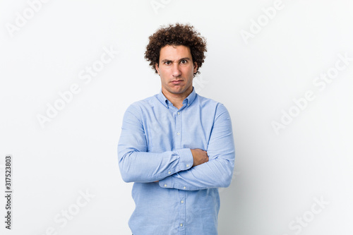 Young curly mature man wearing an elegant shirt unhappy looking in camera with sarcastic expression.