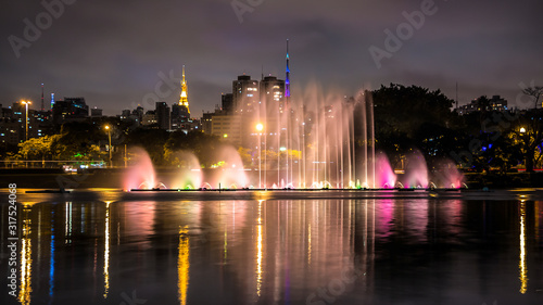 Illuminated Ibirapuera Park At Night. Modern Skyscrapers, Reflection On The Lake And Floating Fountain. .High Water Jets, Miracle Lights Of Metropolis City, Sao Paulo, Brazil.