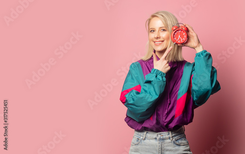 Beautiful blonde woman in 90s clothes with alarm clock